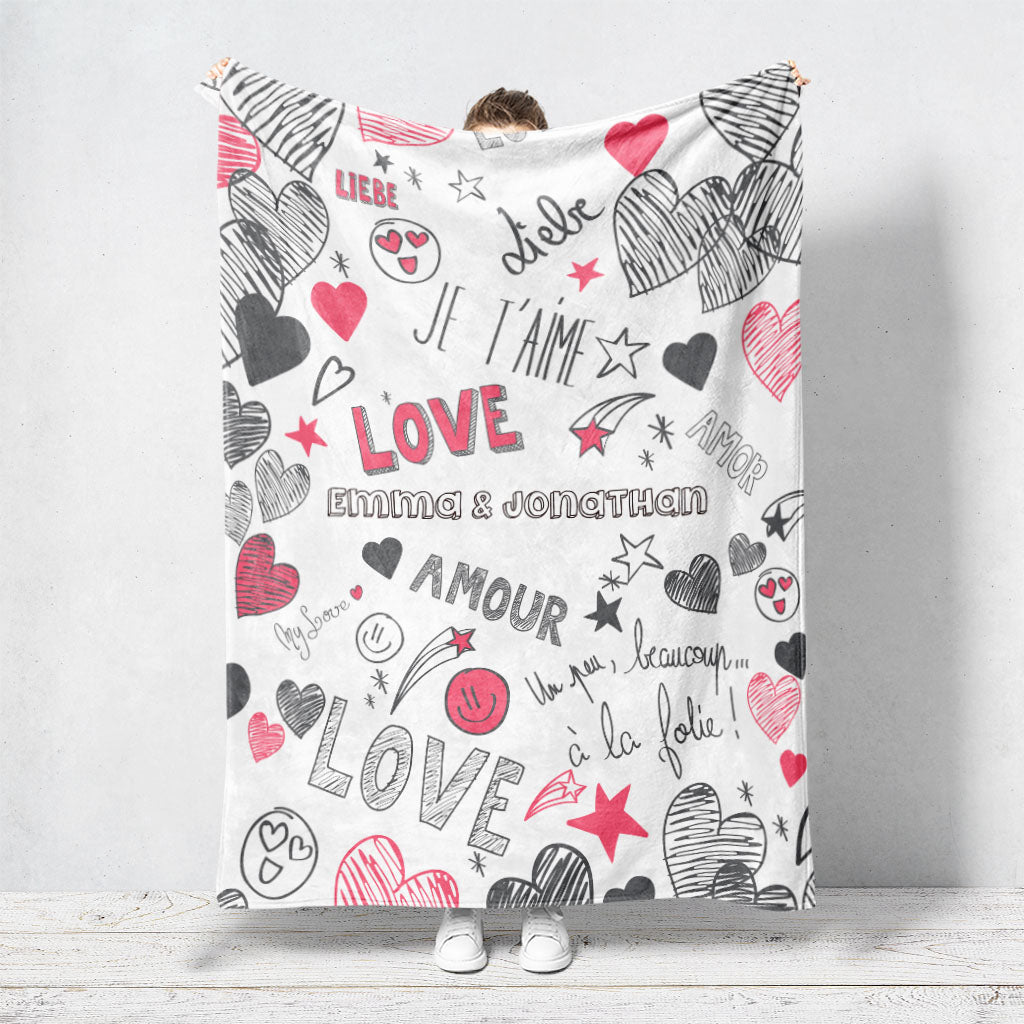 Un plaid personnalisé couple qui représente des smileys et du texte écrit au feutre noir et rouge. Des textes amoureux et notamment le mot “je t’aime” écrit en plusieurs langue. Les prénoms du couple sont personnalisables.