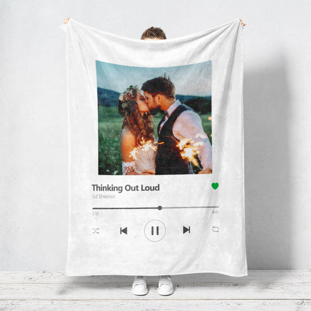 Un plaid personnalisé couple représentant l’interface de Spotify et met en avant une photo du couple avec le titre de leur musique préférée ainsi que le nom de l’artiste. La photo du couple ou du mariage, le titre de la chanson et le nom de l’artiste sont personnalisables.
