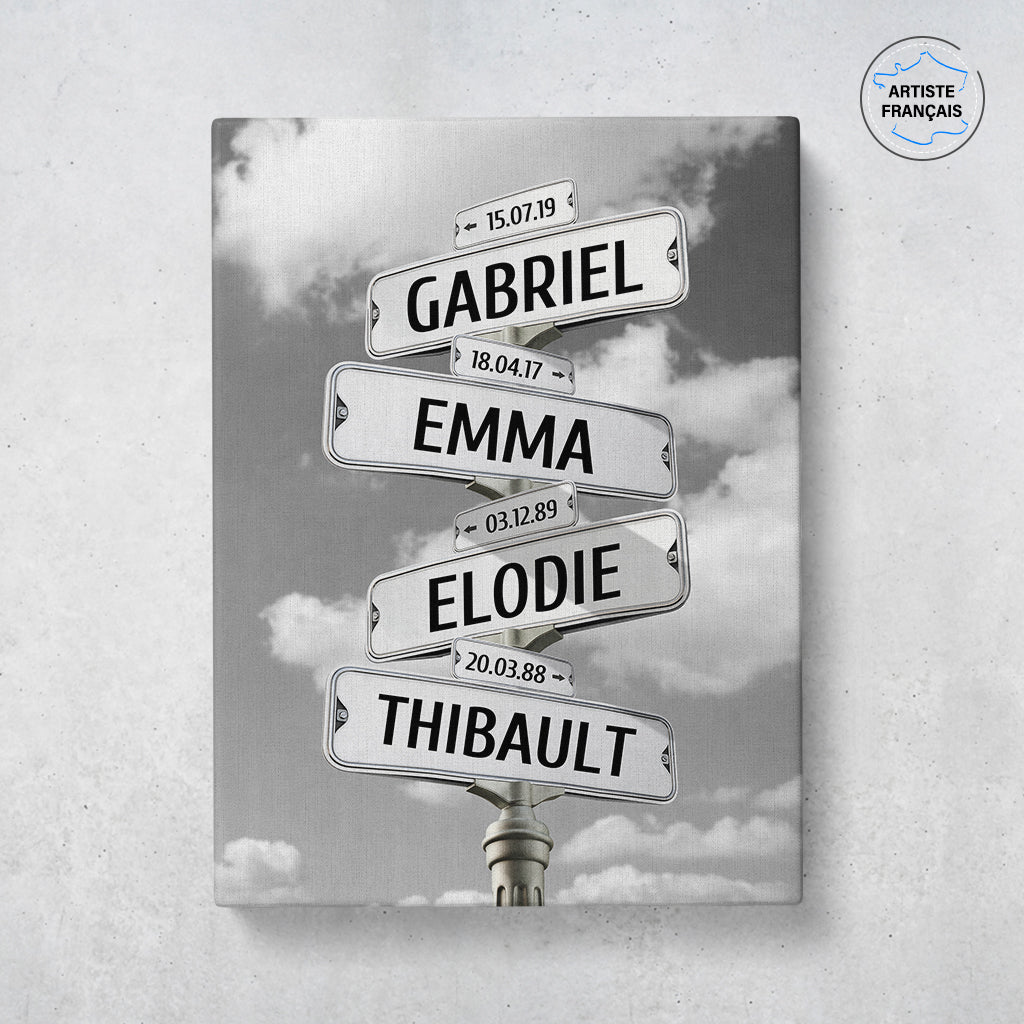 Un tableau personnalisé famille qui représente des panneaux de direction de ville sous un ciel nuageux en noir et blanc. Les prénoms et dates de naissances sur les panneaux sont personnalisables.