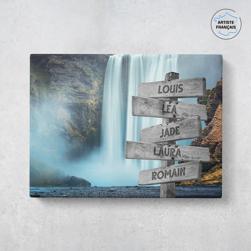 Un tableau personnalisé famille qui représente des panneaux de direction en bois avec des prénoms inscrit dessus en pleine montagne, devant une cascade. Les prénoms sur les panneaux sont personnalisables.