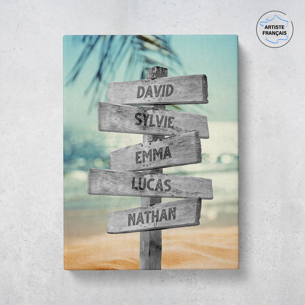 Un tableau personnalisé famille qui représente des panneaux de direction en bois avec des prénoms inscrit dessus dans un décors de plage tropicale, une eau turquoise, un cocotier et un coucher de soleil. Les prénoms sur les panneaux sont personnalisables.