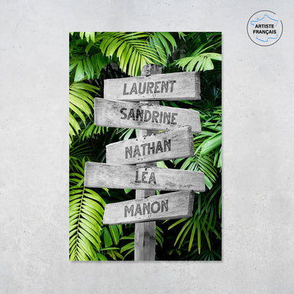Une affiche personnalisée famille qui représente des panneaux de direction en bois avec des prénoms inscrit dessus dans un décors de forêt tropicale avec de grosses feuilles vertes. Les prénoms sur les panneaux sont personnalisables.
