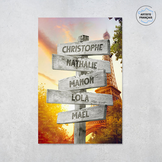 Une affiche personnalisée famille qui représente des panneaux de direction en bois avec des prénoms inscrit dessus dans la ville de Paris avec la Tour Eiffel sous un magnifique coucher de soleil. Les prénoms sur les panneaux sont personnalisables.