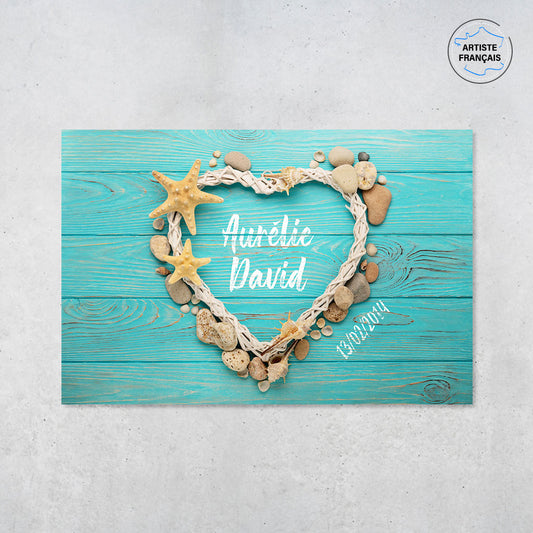 Une affiche personnalisée couple qui représente des coquillages, des galets et du bois formant un coeur sur un fond de planches bleues. Les prénoms au centre du coeur et la date de rencontre du couple sont personnalisables.