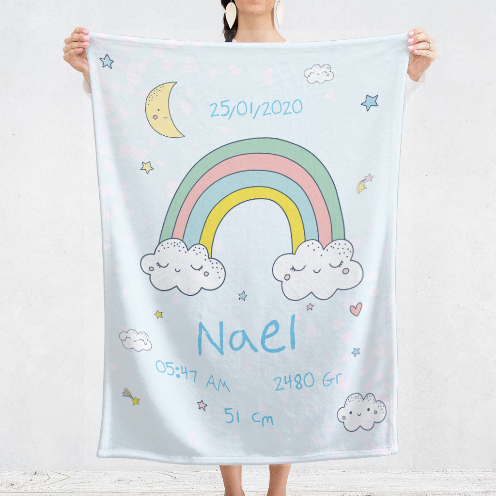 Un plaid bebe personnalisé pour les naissance représentant un ciel étoilé avec un arc en ciel, des étoiles et des nuages au format dessins dans des couleurs pastelles. Ce plaid est dans les tons bleu et donc pour la naissance d’une garçon. Le prénom, la date, l’heure, le poids et la taille de naissance sont personnalisables.